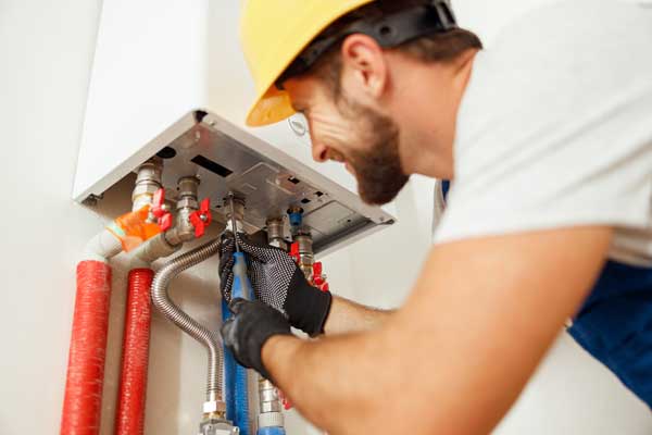 Closeup Of Plumber Using Screwdriver While Fixing Boiler Or Water Heater Working On Heating System In Apartment Boilet Installation Services